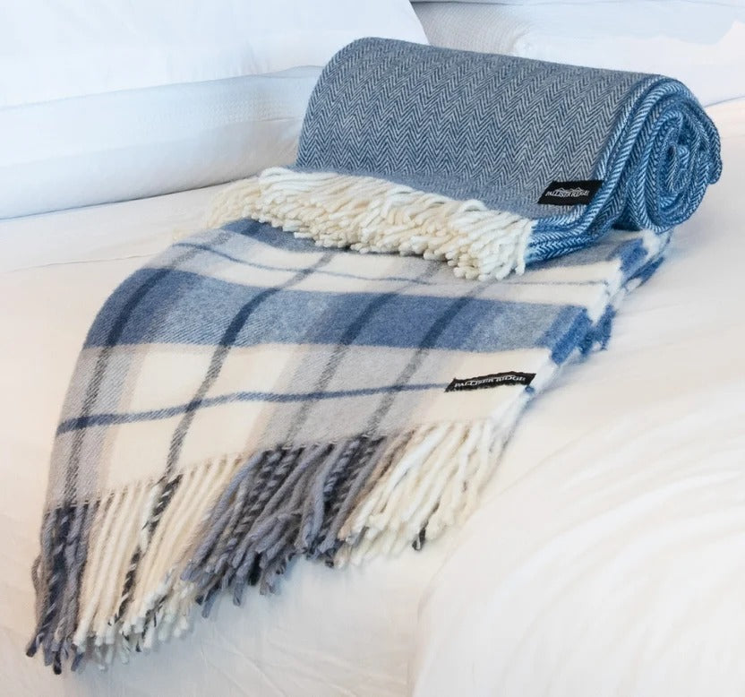 Palliser Ridge Herringbone throw in Royal Blue rolled to show the weave texture, styled on a bed