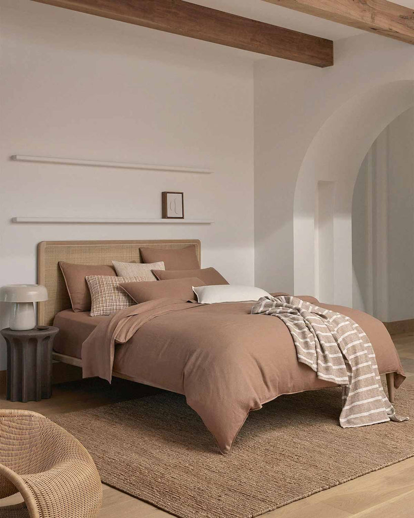 A modern style bedroom, with a soft brown striped throw blanket by Weave Home draped on the bed. 