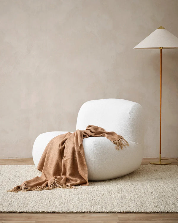 The Baya 'Richmond Sunset' throw blanket drpaed over a chair in a contemporary nz living room