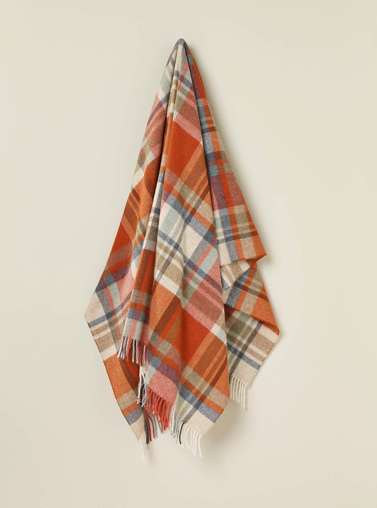A hanging throw in 100% merino wool with a burnt orange and brown check pattern. 