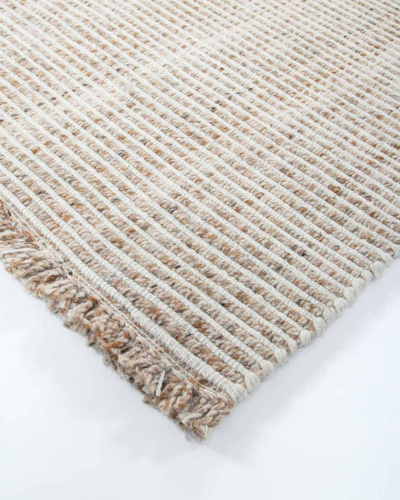 The Rhodes outdoor rug in teak and cream tones, seen close up at the corner showing the stylish weave
