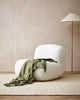 Moss green wool-blend throw blanket with tasseled fringe, draped over a chair in a contemporary living room