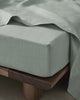 Sage green flat sheet in premium French flax linen, on a bed with a fitted sheet