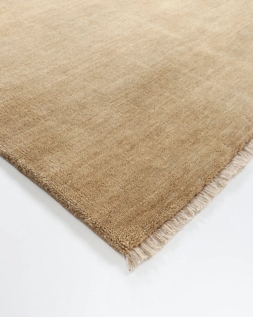 Corner of the cut pile of the Baya Sandringham Wool rug in colour 'putty', highlighting the small fringe detail