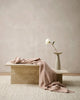 The Baya 'Cromwell Blush' throw blanket draped on a table in a contemporary living room