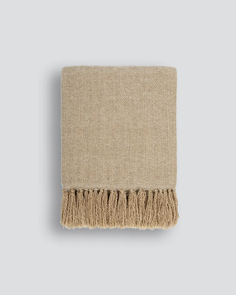 Light brown throw blanket with tasseled fringe, the Baya 'Richmond Putty' seen folded