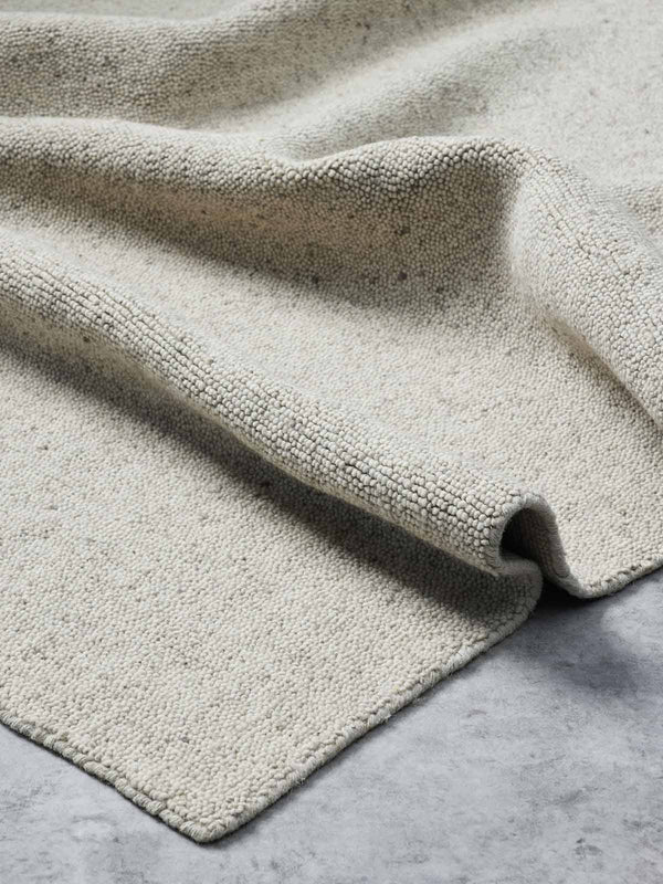 A light beige warm, looped style 100% wool floor rug from Tribe Home