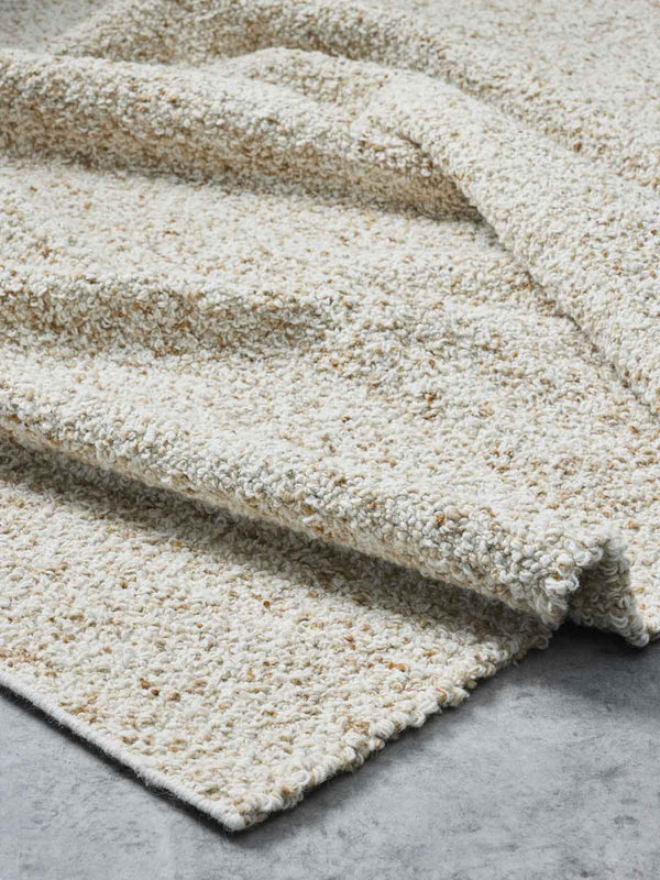 A 100% NZ wool floor rug in warm neutral tones, with scatterings of ivory, camel, and beige. The rug has a gorgeous looped pile bringing texture. By Tribe Home
