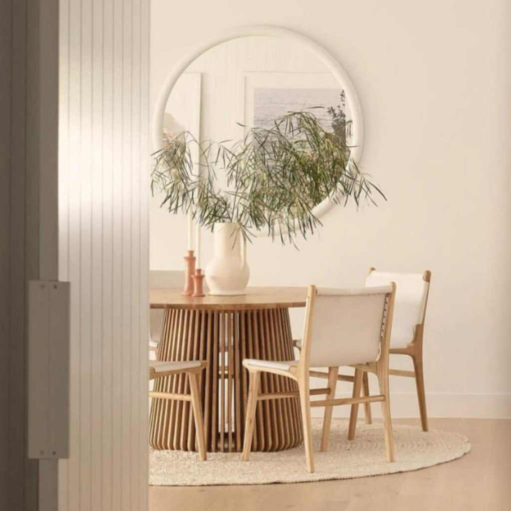 A sophisticated dining room in neutral tones with a hand braided jute floor rug in white underneath the table. 