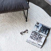 A whitewashed jute floor rug, braided in a round style, in a stylish coastal living room. 