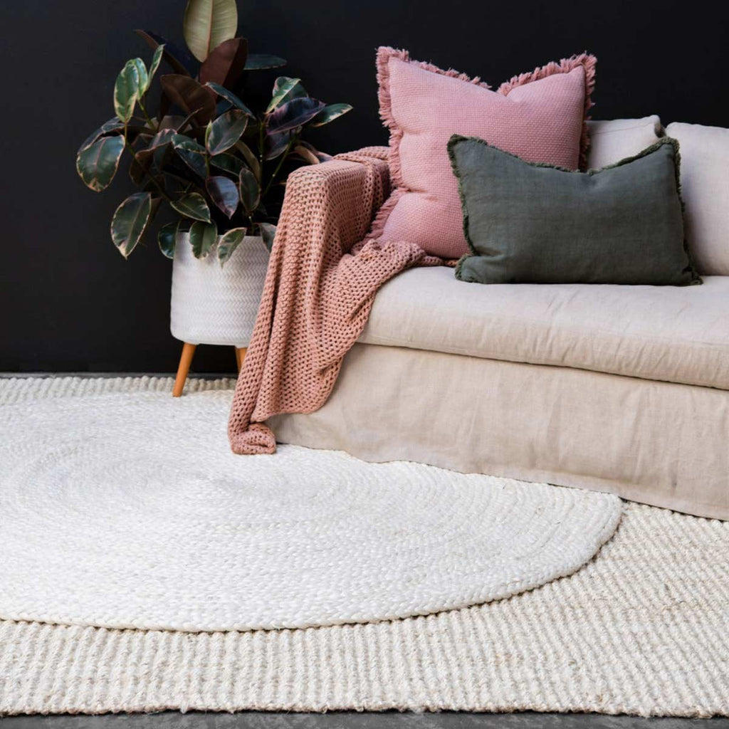 A braided jute floor rug in a chic living room, whitewashed for a sophisticated vibe. 