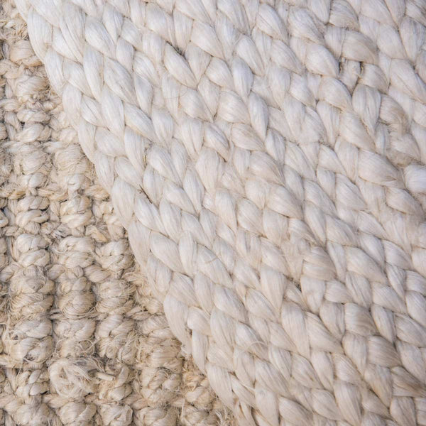 A close up of the hem of a whitewashed braided natural jute floor rug. 