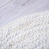 A close up of the edge of a braided jute white washed round floor rug. 