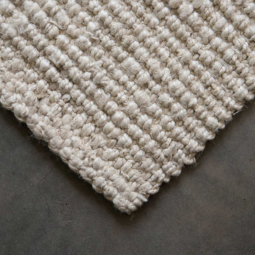 A corner of a white washed jute floor rug. 