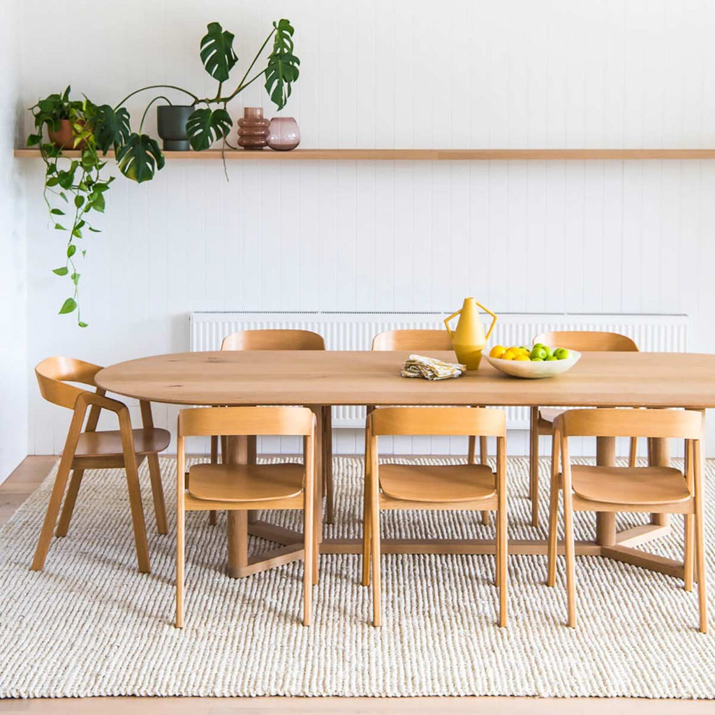 A dining room with a minimalist white floor rug under the table, made with durable jute fibres in a boucle weave. 