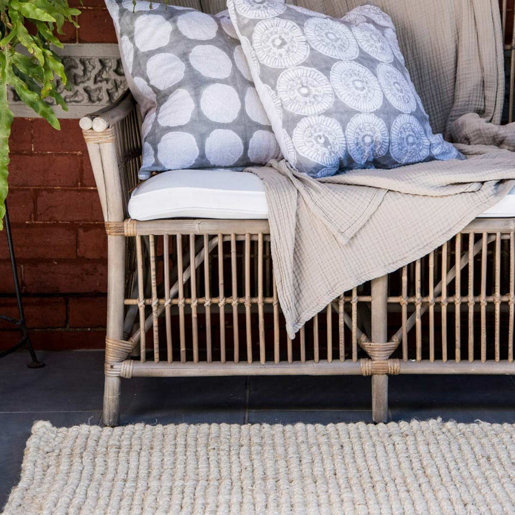 An outdoor area with a soft cream floor rug made in a boucle style weave with jute. 