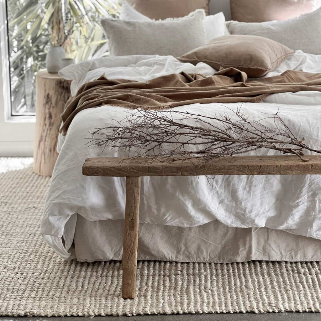 A bedroom in neutral tones with a delicate white floor rug made with durable jute fibres. 