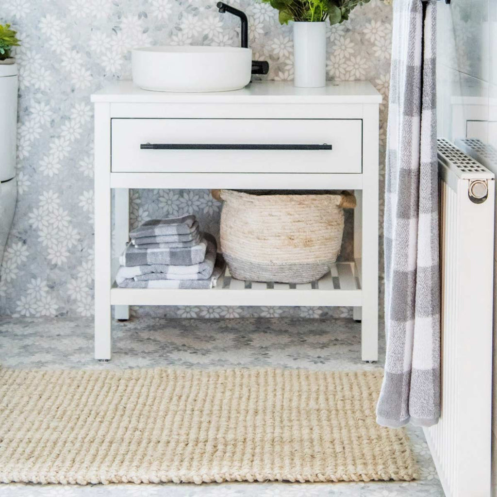 A bathing area with a white jute floor mat in a boucle weave. 