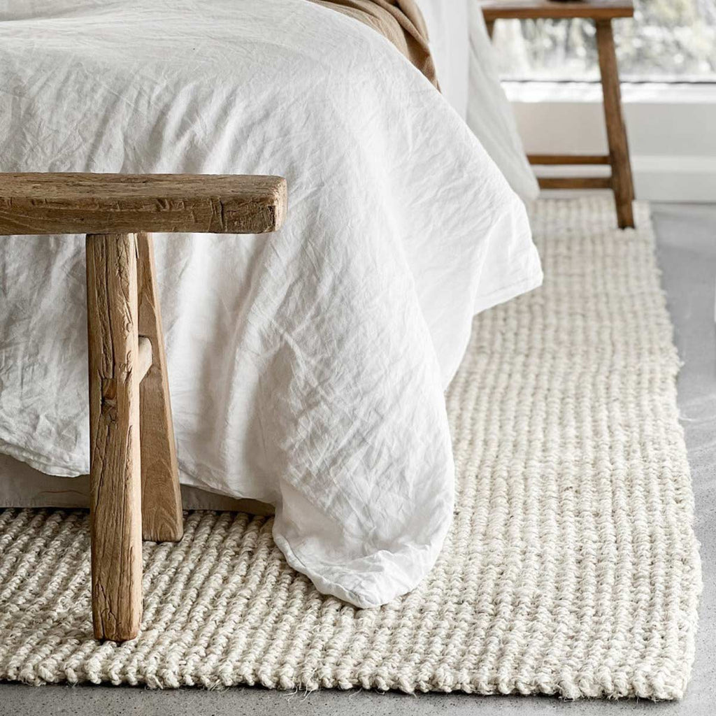 A soft off-white floor rug made with jute fibres in a bedroom. 