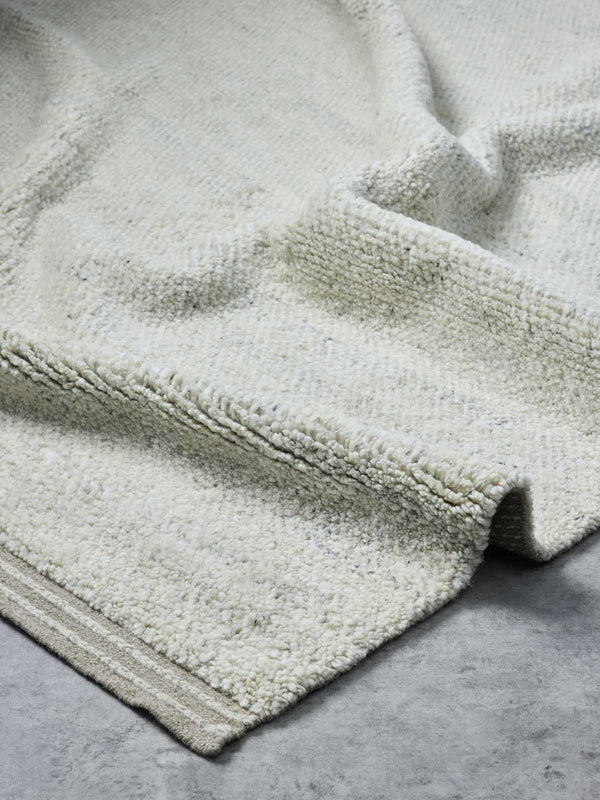 A luxurious, deep-cut pile floor rug in 100% NZ wool made by Tribe Home. A soft beige fawn colour, with the depth of the pile offset by a linear border. 