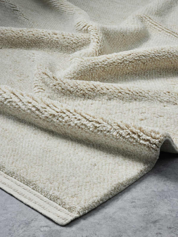 A luxurious, deep-cut pile floor rug in 100% NZ wool made by Tribe Home. A soft, warm beige and honey colour, with the depth of the pile offset by a linear border. 