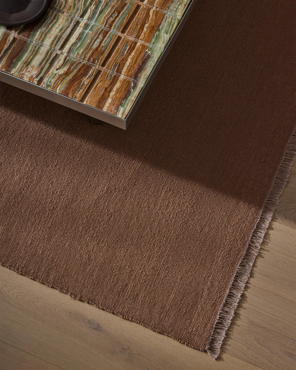 Weave Home Jacqueline wool rug in Rosewood, close view of the flatweave beneath a stone-topped table