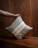 Weave Home Ottavio cushion in Lagoon held against a walnut-panelled shelf.