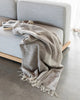 Baya 'Flagstone' NZ wool throw blanket in beige brown tones, draped on a couch in a stylish  home