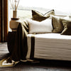 A gorgeous white couch featuring an array of cushions in tones of green and white by Eadie Lifestyle, as well as the olive green throw blanket in Zen 